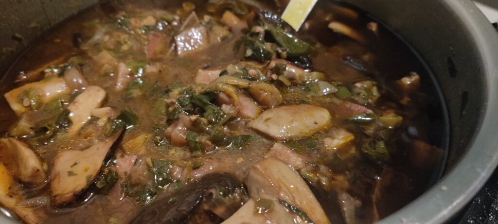 Large pot of okra soup with greens and mushrooms.