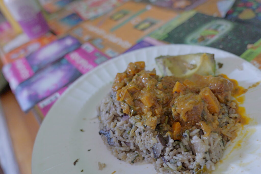 A mound of flavored rice draped in groundnut soup with avacado slice on the side